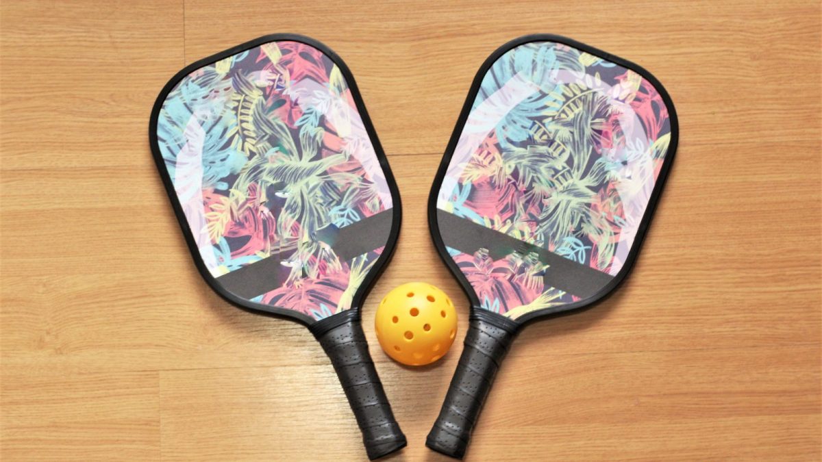 two pickleball paddles on ground with pickleball between them